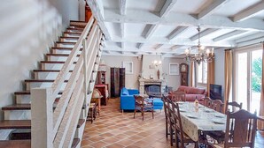 A spacious living area with a staircase, a fireplace, a dining table set for four, and a large window providing natural light. - Lovely home in Saint-Thurien with WiFi (Saint-Thurien)