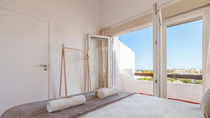 Ein Schlafzimmer mit einem Bett, einem Fenster mit Blick auf die Stadt und einer Tür.