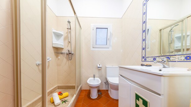 Un bagno con box doccia in vetro, un bidet, un water e un lavabo con specchio.