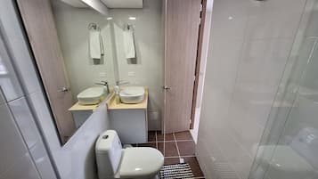 A modern bathroom with two sinks, a toilet, and a glass shower enclosure.