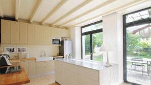 Une cuisine moderne avec des poutres en bois, un îlot central et une grande fenêtre.