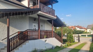 Une maison à deux étages dotée d’un balcon, d’un escalier et d’une pelouse bien entretenue.
