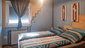 Une chambre à coucher avec un lit, une fenêtre avec des rideaux, un radiateur et des œuvres d’art accrochées au mur.