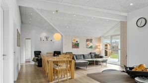 A spacious living room with a wooden dining table, grey sofa, and a large window providing a view of the outdoors. - Awesome home in Tarm with WiFi (Tarm)