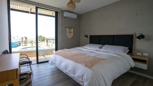 Een moderne slaapkamer met een groot bed, een houten bureau en uitzicht op een zwembad.