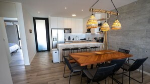 Een moderne keuken met witte kasten, een houten eettafel met stoelen en hangende pendellampen.