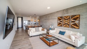 Een moderne woonkamer met een bank, een salontafel en een eethoek op de achtergrond.