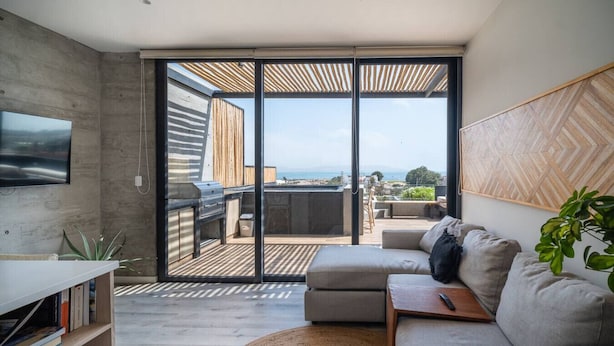 A modern living room with a large sliding glass door leading to an outdoor patio.