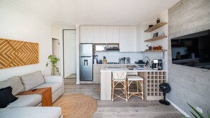 A modern kitchen with white cabinets, a stainless steel refrigerator, and a built-in island with bar stools.
