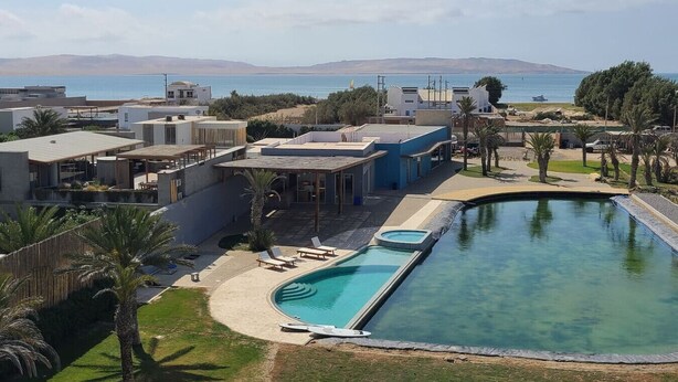 A modern hotel with a pool, outdoor seating, and a view of the sea. - Cozy & Classy flat in Paracas Bay with Balcony View on the Saltwater Lagoon (Paracas)