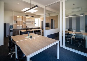 A modern office space with a large wooden table, black office chairs, and a glass partition. - Beautifully Decorated Apt with Ocean View, Balcony & Kamado next to the Bay (Paracas)