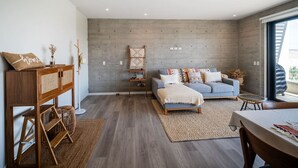 Un salón moderno con una pared de concreto gris, un sofá gris y una mesita de madera.