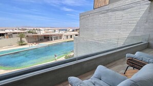 Un balcón con vista a una piscina y un paisaje desértico.