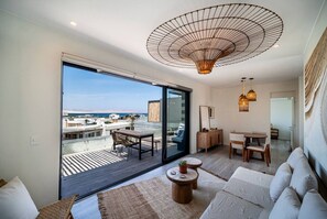 Een moderne woonkamer met een grote schuifpui naar een balkon, een ronde houten salontafel, een bank en een hanglamp.