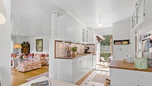 A spacious kitchen with white cabinetry, a dining area with a floral sofa, and a view of the outdoors.