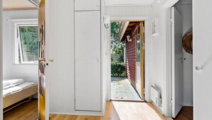 A room with a bed, a white door, and a view of a garden through an open door.