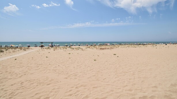 A sandy beach with a clear sky and a few clouds. There are umbrellas and people scattered along the shore. - Cozy apartment in Mondragone with WiFi (Mondragone)