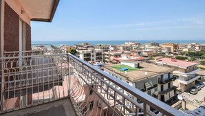 A residential area with a view of the sea, featuring multi-story buildings, a balcony with a metal railing, and a clear sky. - Cozy apartment in Mondragone with WiFi (Mondragone)