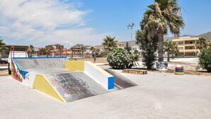 A skate park with ramps and graffiti, surrounded by palm trees and buildings. - Cozy apartment in Mondragone with WiFi (Mondragone)