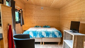 Une pièce de style cabane en bois, comprenant un lit, une chaise, un bureau et un téléviseur.