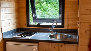 Une cuisine de taille réduite, dotée d’une fenêtre, d’un évier et d’une cuisinière.