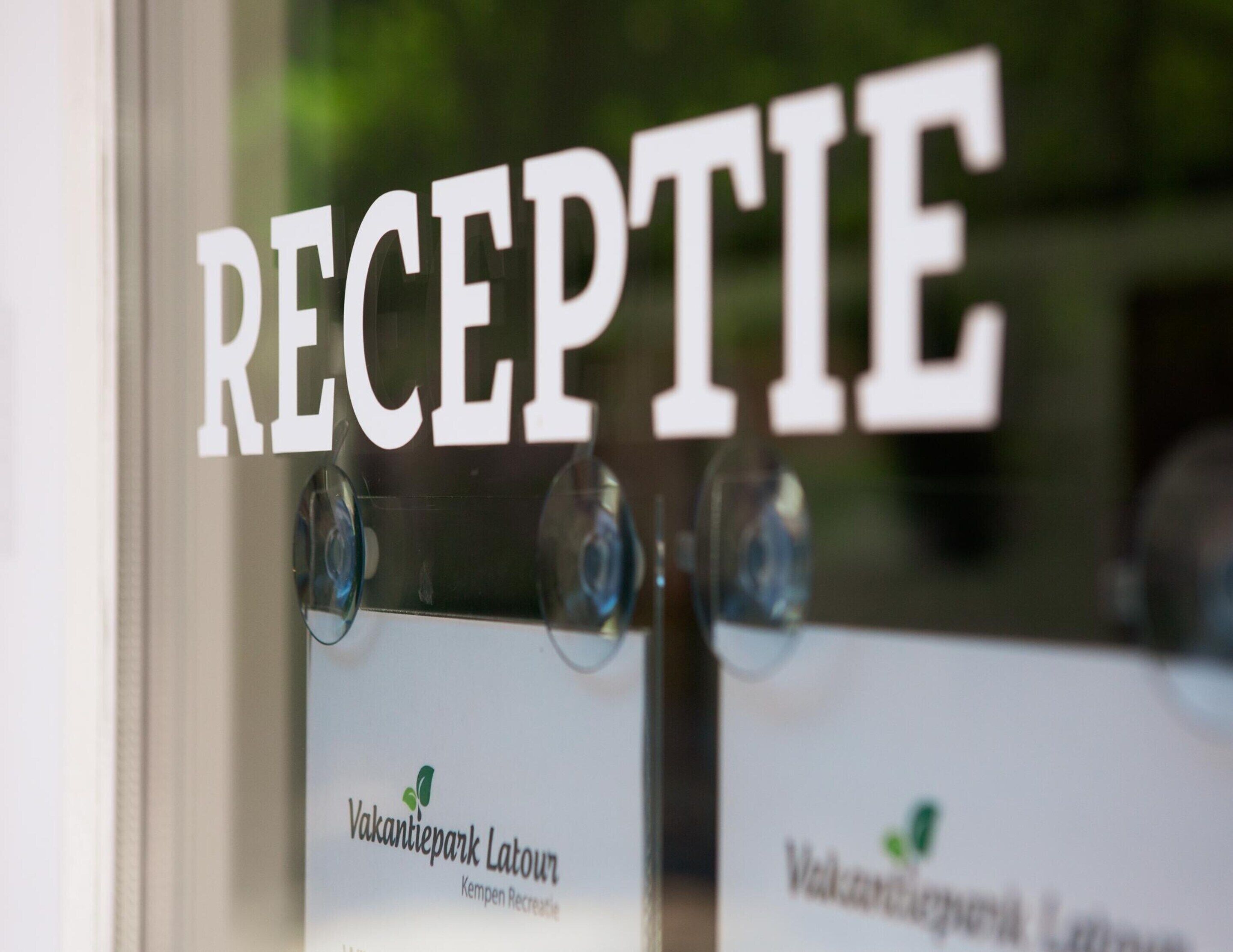 A reception area with a sign that reads "RECEPTIE" and two signs below it that say "Vakantiepark Latour" and "Kempen Recreatie".