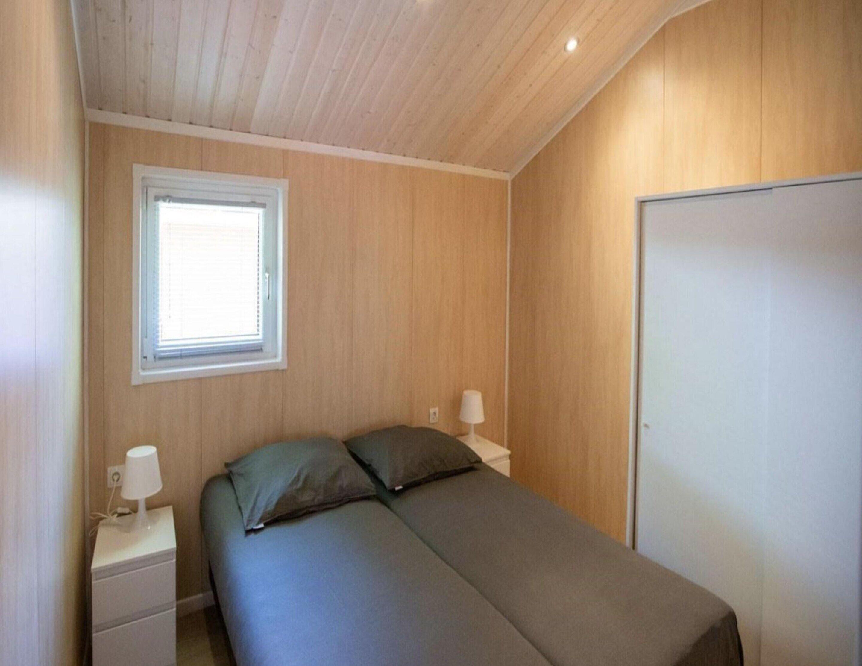 Une chambre à coucher avec un lit, une table de chevet, une fenêtre et une armoire.