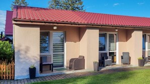 A two-story building with a red-tiled roof, large windows, and a small outdoor seating area with wicker furniture. - Cozy home in Rekowo with swimming pool (Rekowo)
