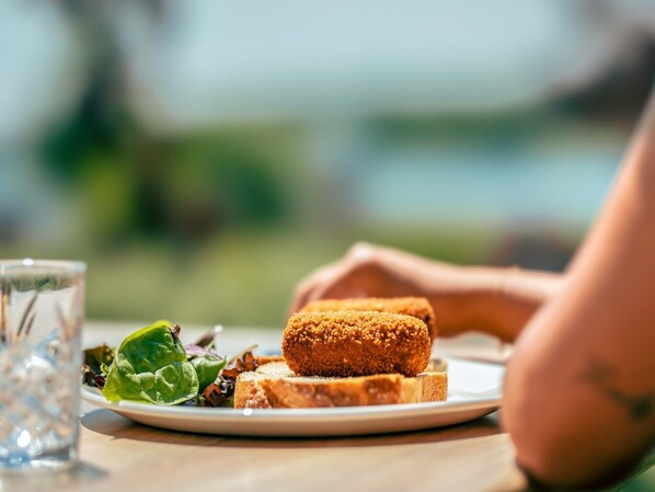 A plate with a breaded item and a salad on a table outdoors.