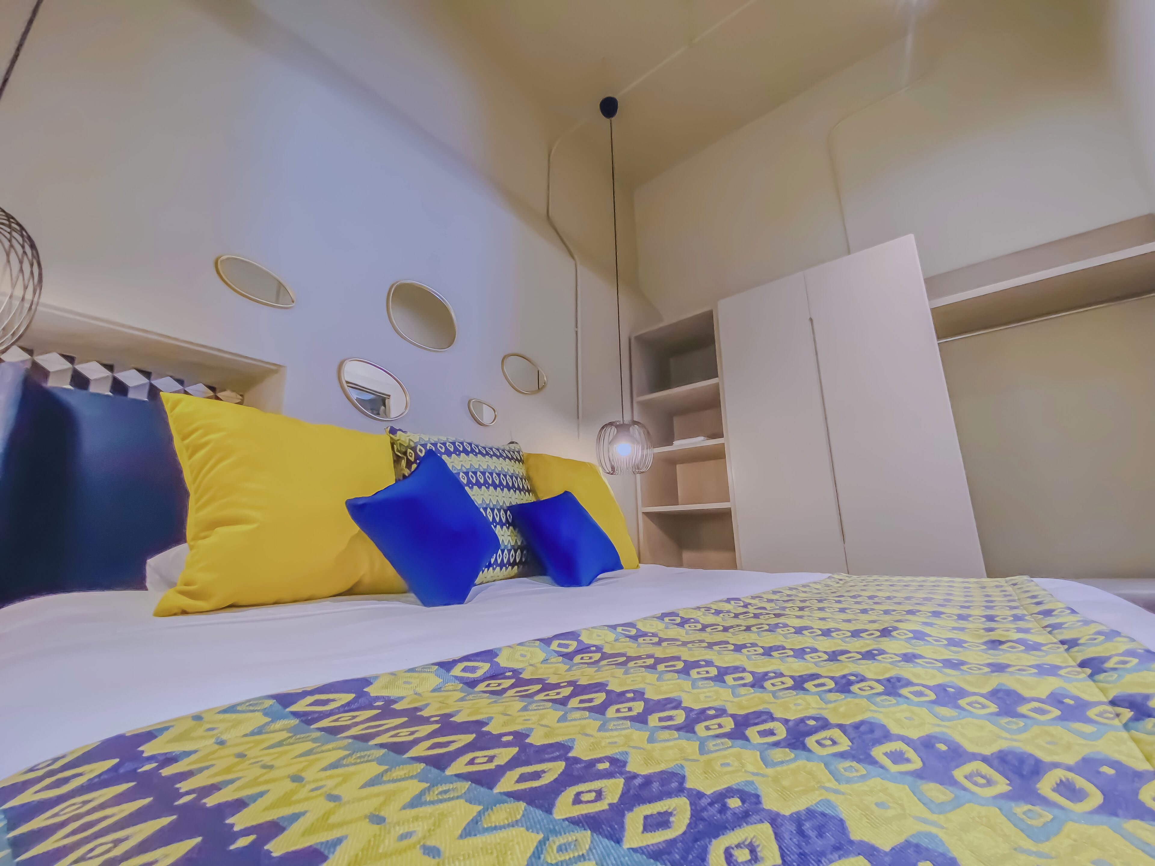 A bedroom with a bed, a wardrobe, and a mirror on the wall.