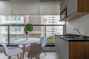 A modern kitchen with a black countertop, a sink, and a window overlooking a cityscape. - Akile W Perdizes (São Paulo)
