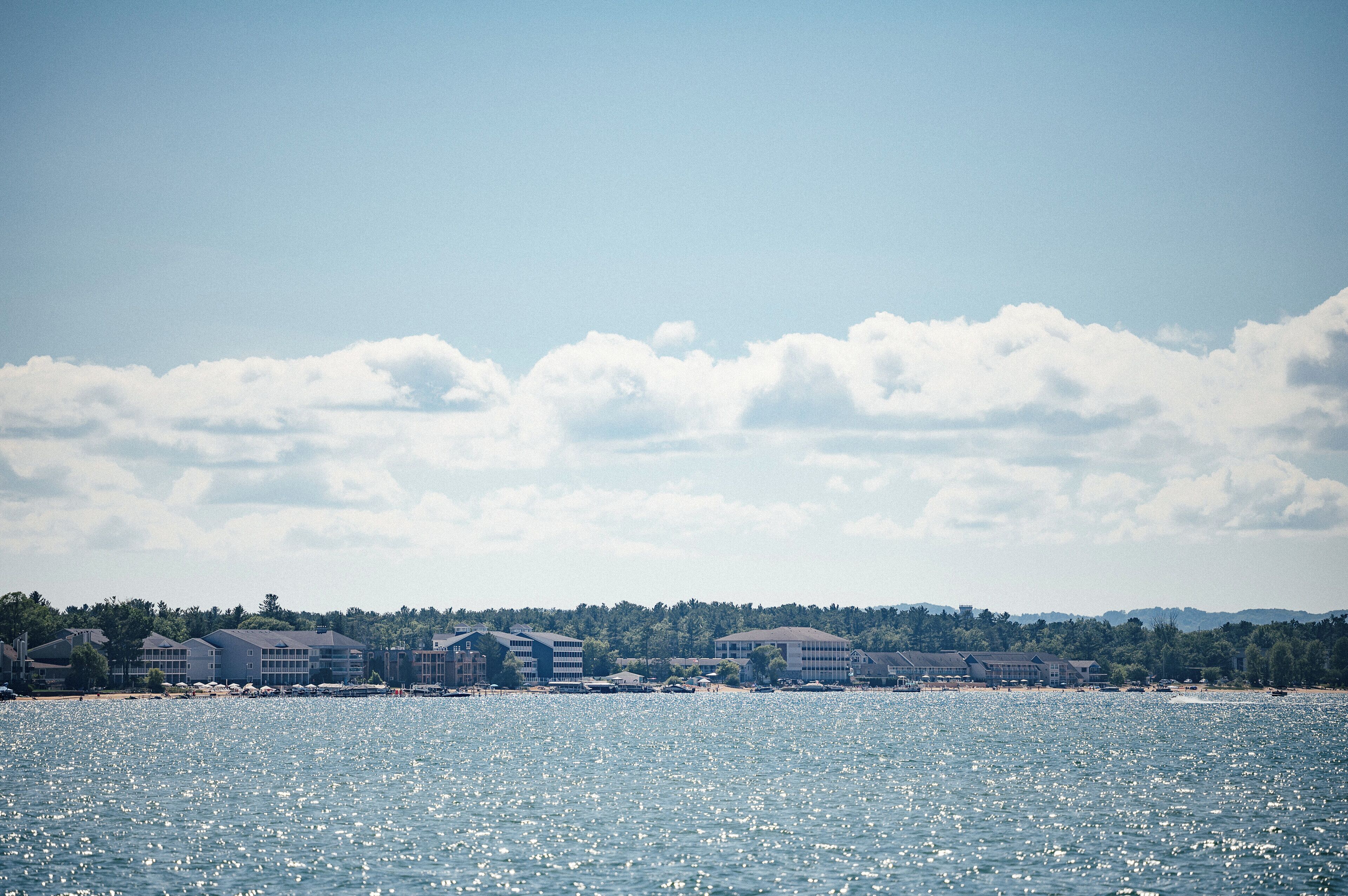 A coastal hotel with multiple buildings, a beach, and a clear sky.
