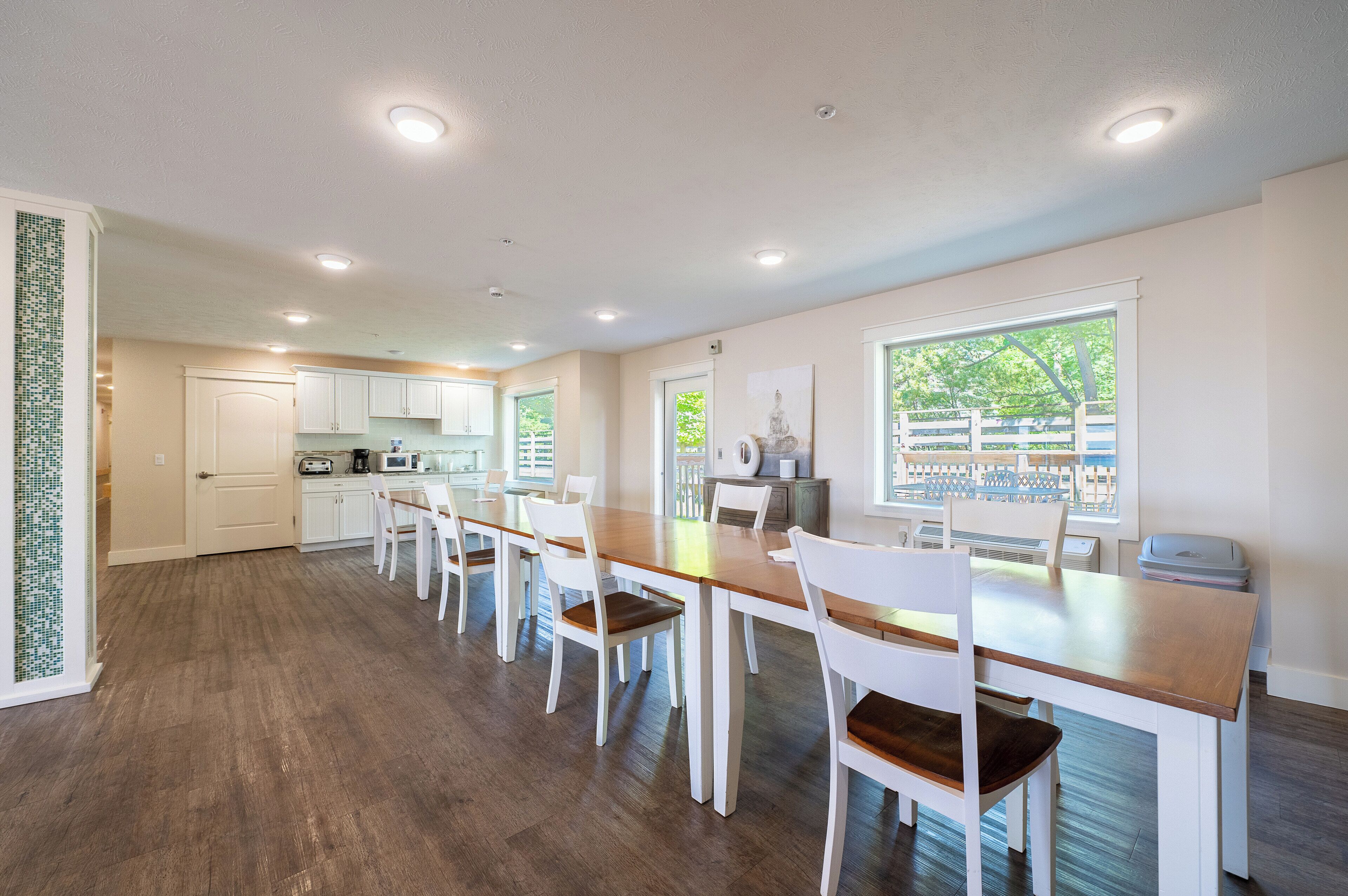 Une cuisine spacieuse avec des meubles blancs, un plan de travail en bois et un coin repas doté de chaises blanches.