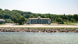 Et hotel med en central bygning, en parkeringsplads og en flod i forgrunden.