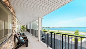 En balkon med tag, udsigt til et sølandskab og en parkeringsplads.