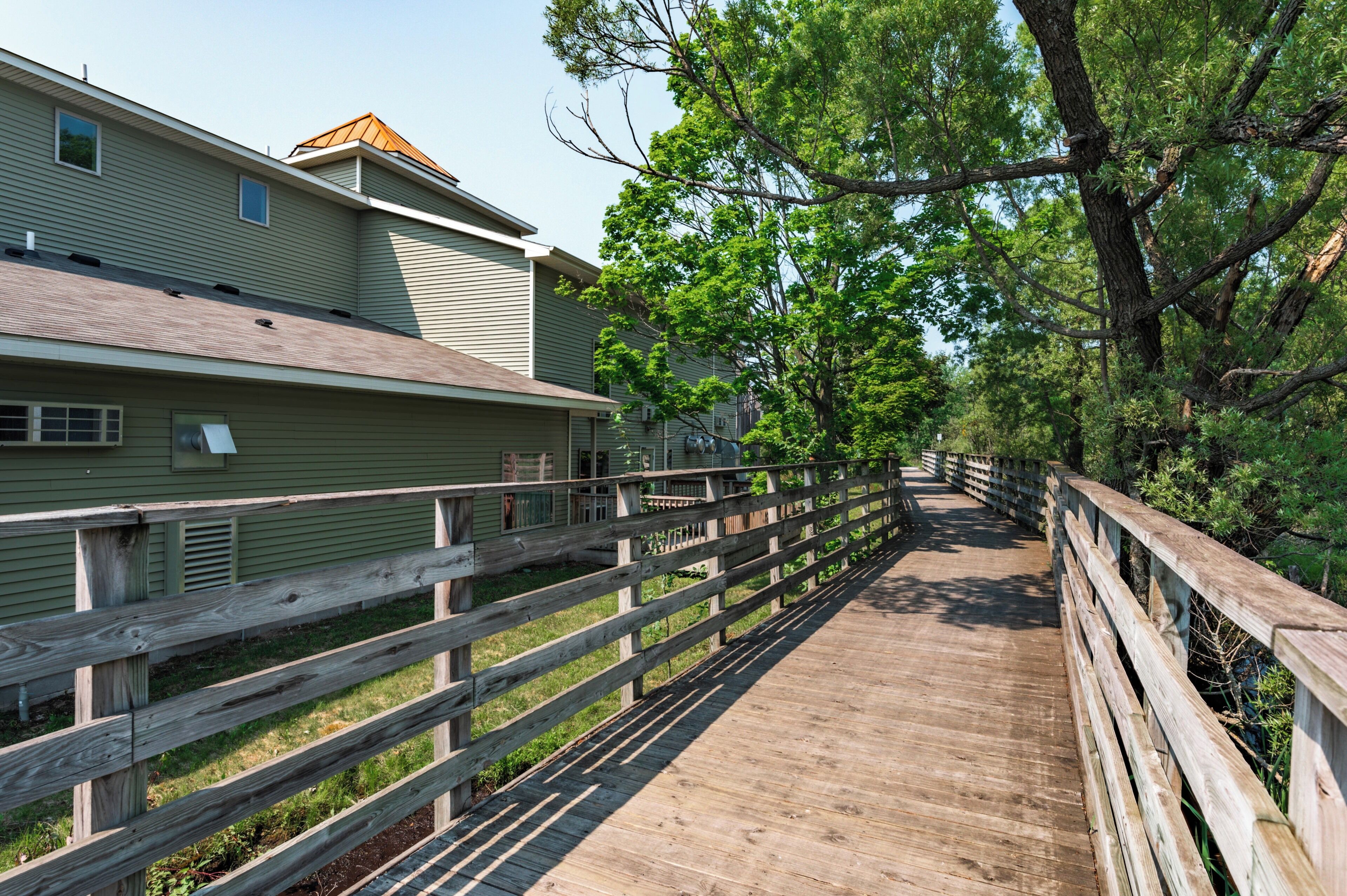 A wooden boardwalk leading to a building with a sloped roof and a small window.