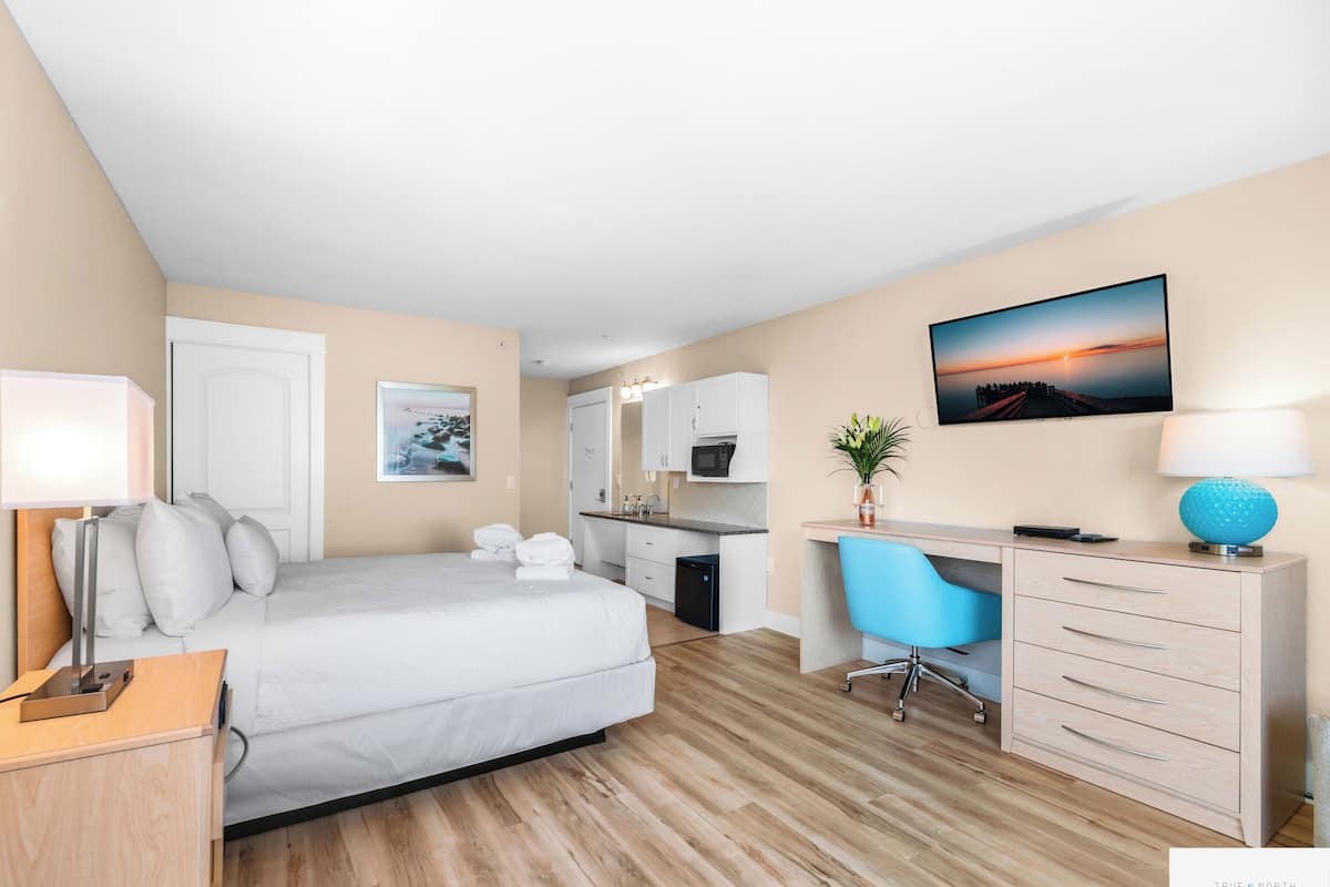 A hotel room with a bed, desk, chair, and a TV mounted on the wall.