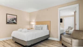 Una habitación de hotel con cama, lámpara de noche, una silla, televisor y un cuadro en la pared.