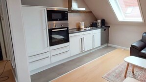Une cuisine compacte dotée d’appareils électroménagers modernes, un coin repas et une lucarne.