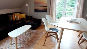 Un salon moderne comprenant un canapé, un banc, une table à manger avec des chaises et une grande fenêtre avec des rideaux.