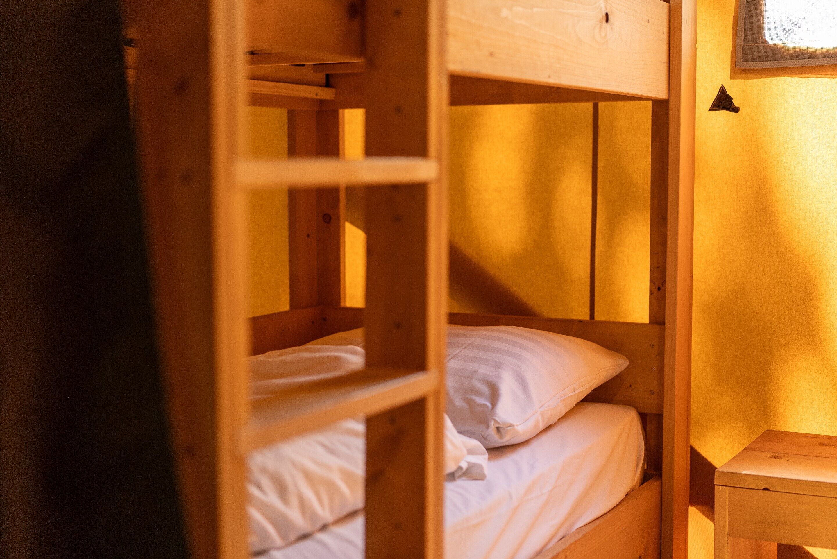 A bunk bed with white bedding and a wooden headboard.