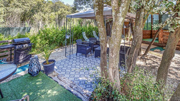 An outdoor patio with a grill, seating area, and a patterned rug. - Cozy (sta)caravan in Pernes-les-Fontaines (Pernes-les-Fontaines)