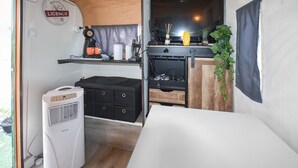 A compact kitchenette with a coffee maker, a small shelf with items, a black cabinet, and a plant. - Cozy (sta)caravan in Pernes-les-Fontaines (Pernes-les-Fontaines)