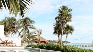 A poolside area with lounge chairs and a wooden deck. - BT Homes - Tankah Beachfront (Tulum)