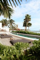 Una piscina al aire libre, sombrillas, sillones reclinables de piscina