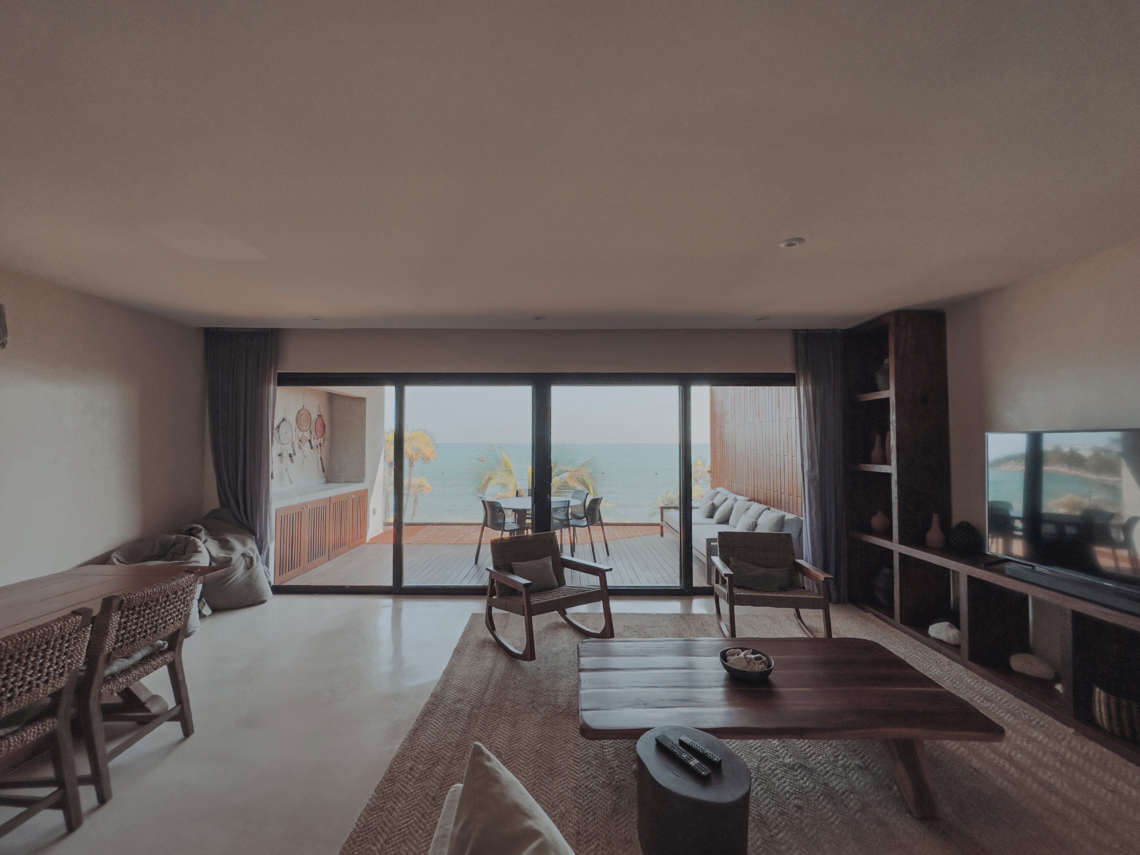 Un salon moderne doté d’une grande porte-fenêtre coulissante donnant sur un balcon avec vue sur la mer.