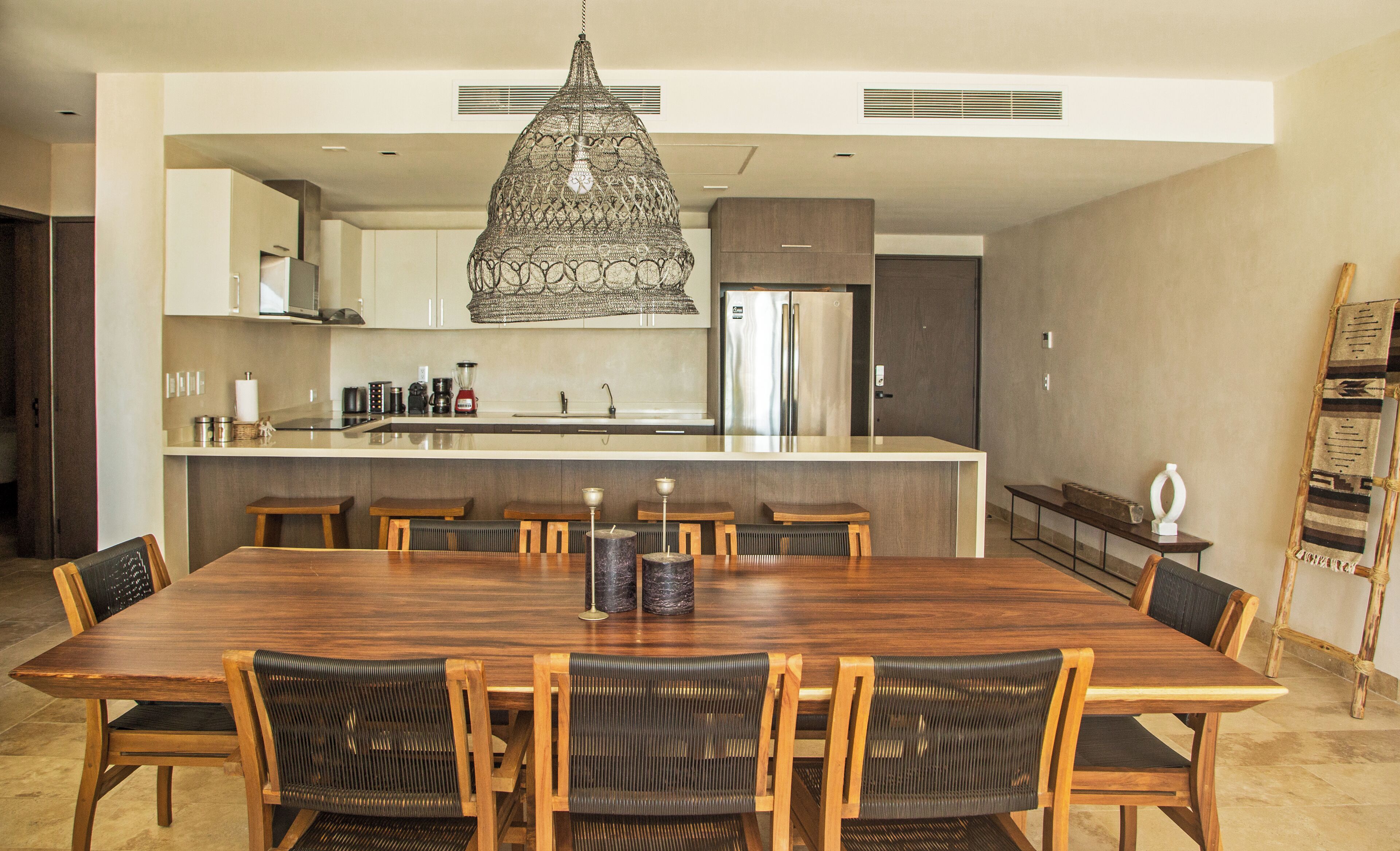 A modern kitchen with a central island, stainless steel appliances, and a hanging light fixture.