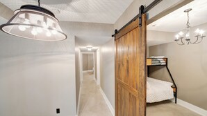 A hallway with a hanging light fixture, a wooden sliding door, a bunk bed, and a chandelier. - Unique Industrial designer studio (Aurora)
