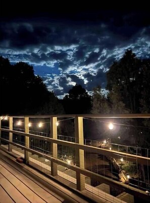 A nighttime view of a modern building with a glass facade, illuminated by string lights, set against a backdrop of a cloudy sky. - Private/Cozy 2 bedroom mountain cabin Serenity now (Regina)