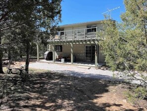 A two-story house with a covered patio, a barbecue area, and a large window.